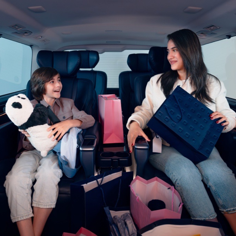 A mother and her child inside a car full of bags.