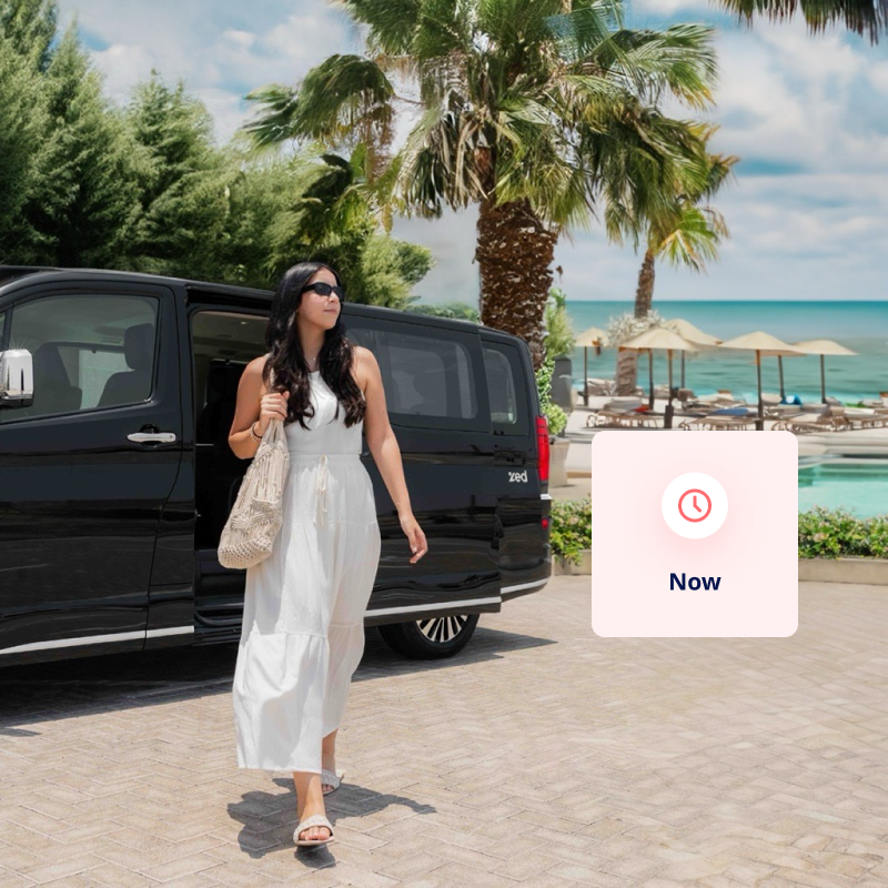 A man in a suit about to enter a van with the Dubai skyline in the background.