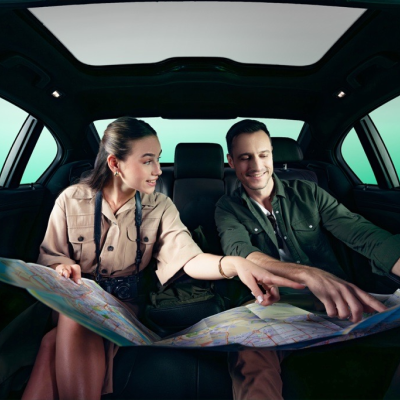 A couple inside a car with a paper map open.